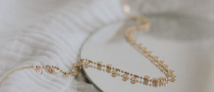 gold necklace on white textile