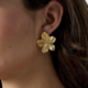 Boucles d’oreilles Alina en acier inoxydable doré, motif fleur texturé, finition brillante.