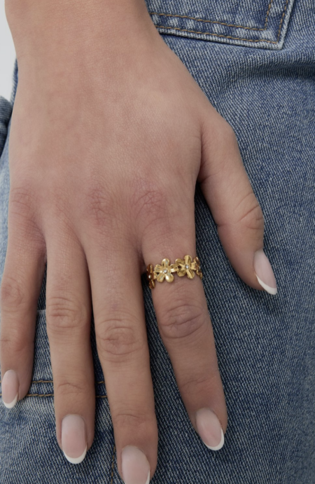 Bague florale en acier inoxydable doré composée de fleurs délicates, portée seule sur fond clair